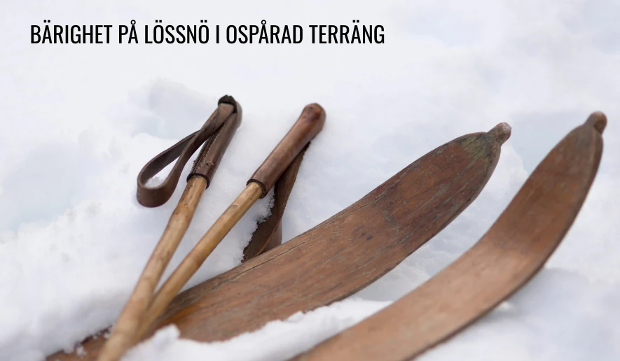 Ett par gamla träskidor och trästavar ligger på lössnö
